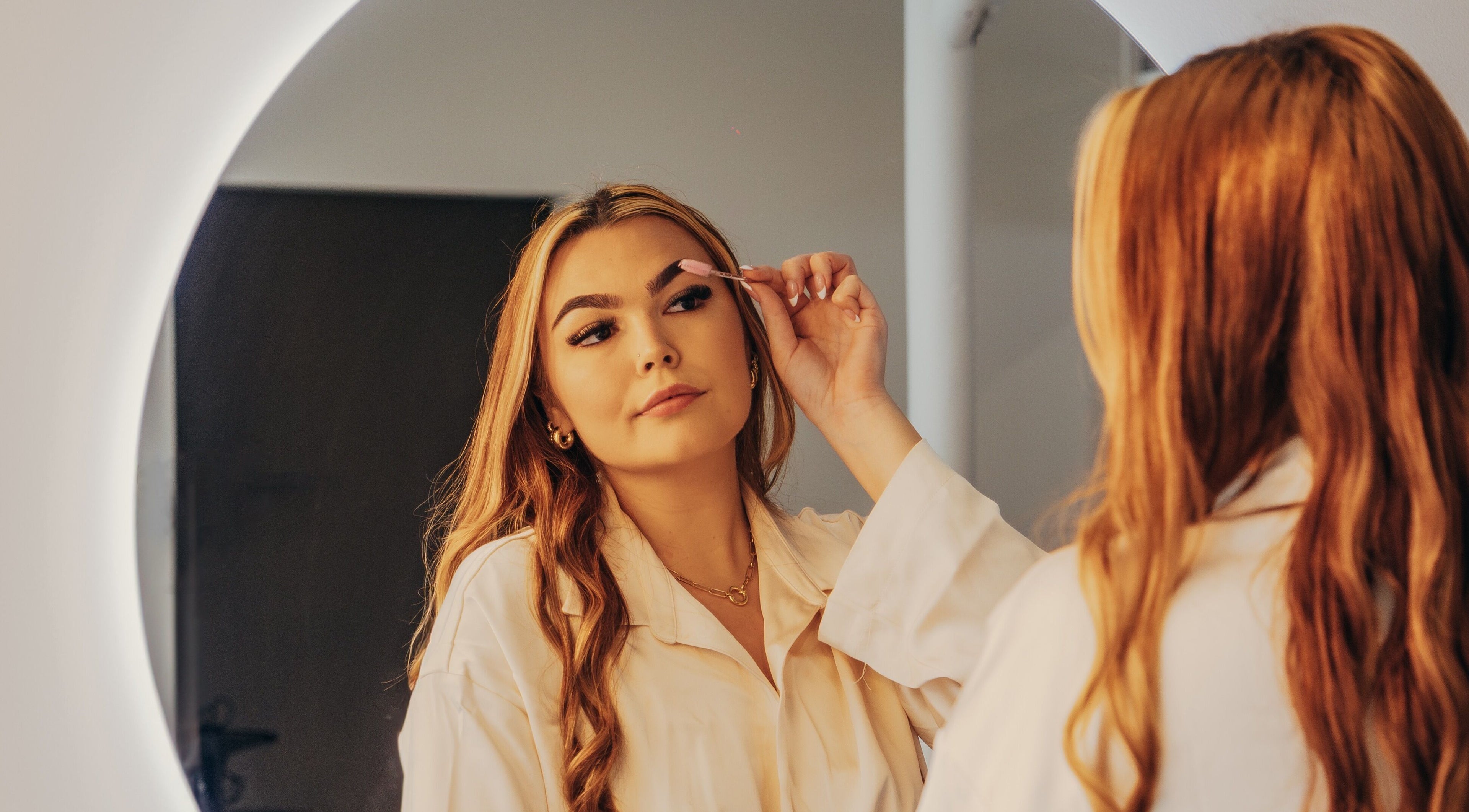 Woman grooming eyebrows at Lux Aesthetix mirror, Mooloolaba, Queensland, AU.