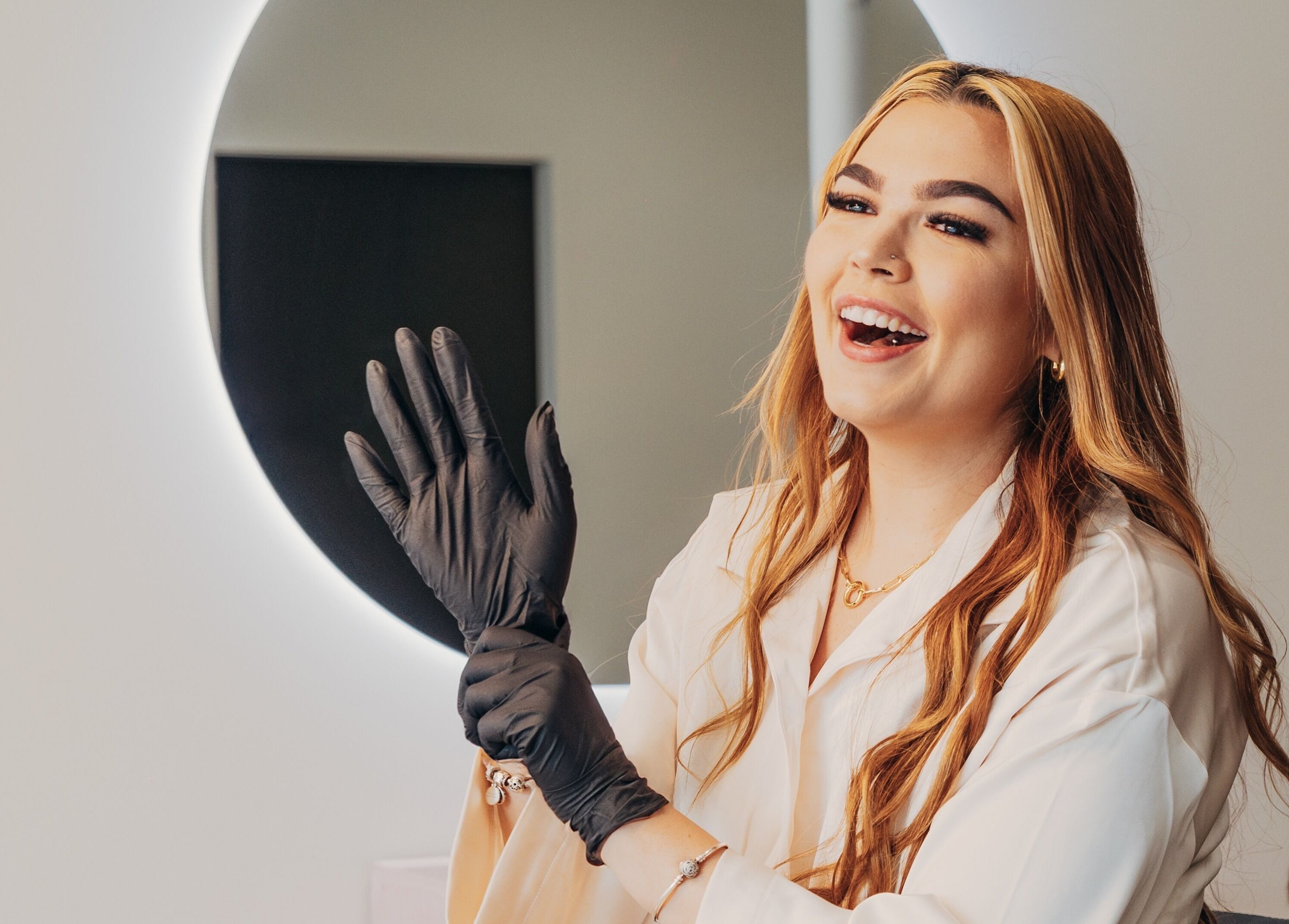 Professional smiling at Lux Aesthetix in Mooloolaba, Queensland, AU, preparing with gloves for a session.