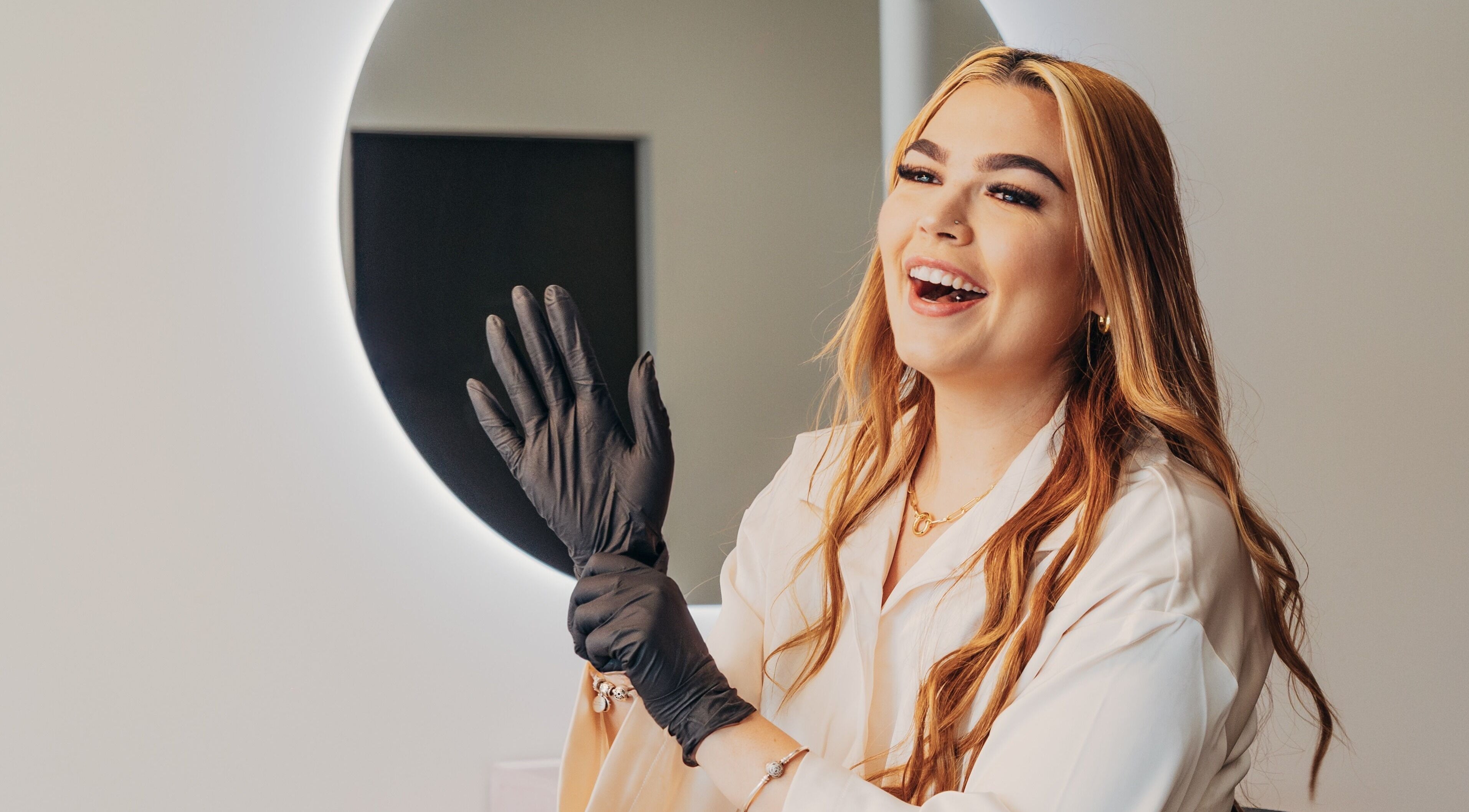 Professional smiling at Lux Aesthetix in Mooloolaba, Queensland, AU, preparing with gloves for a session.