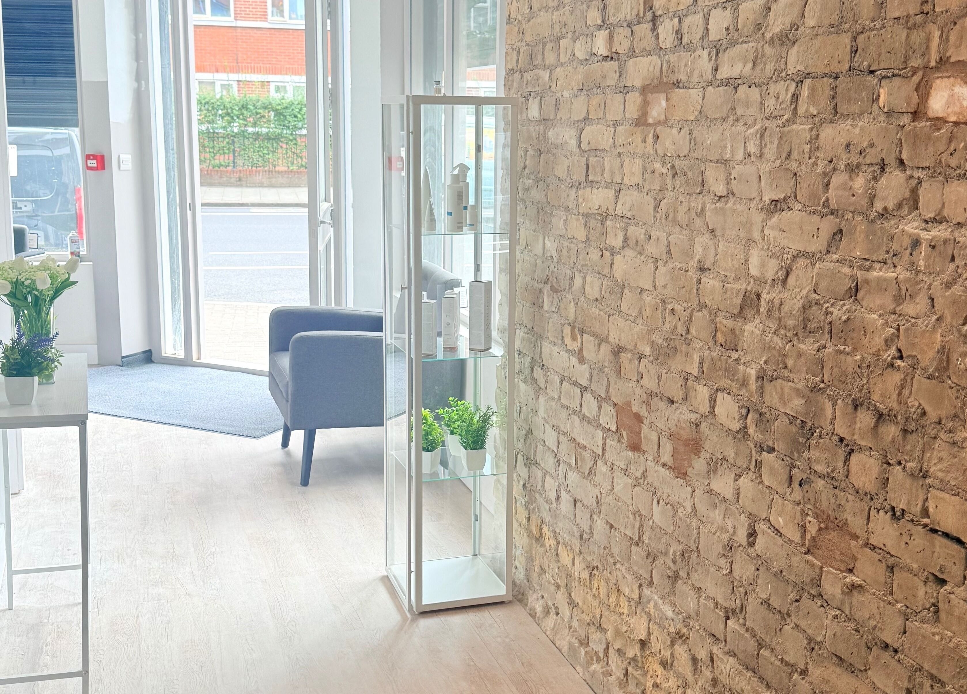 Chic entry with rustic brick wall at Facefull Aesthetics, London, England, GB. Bright and inviting decor.