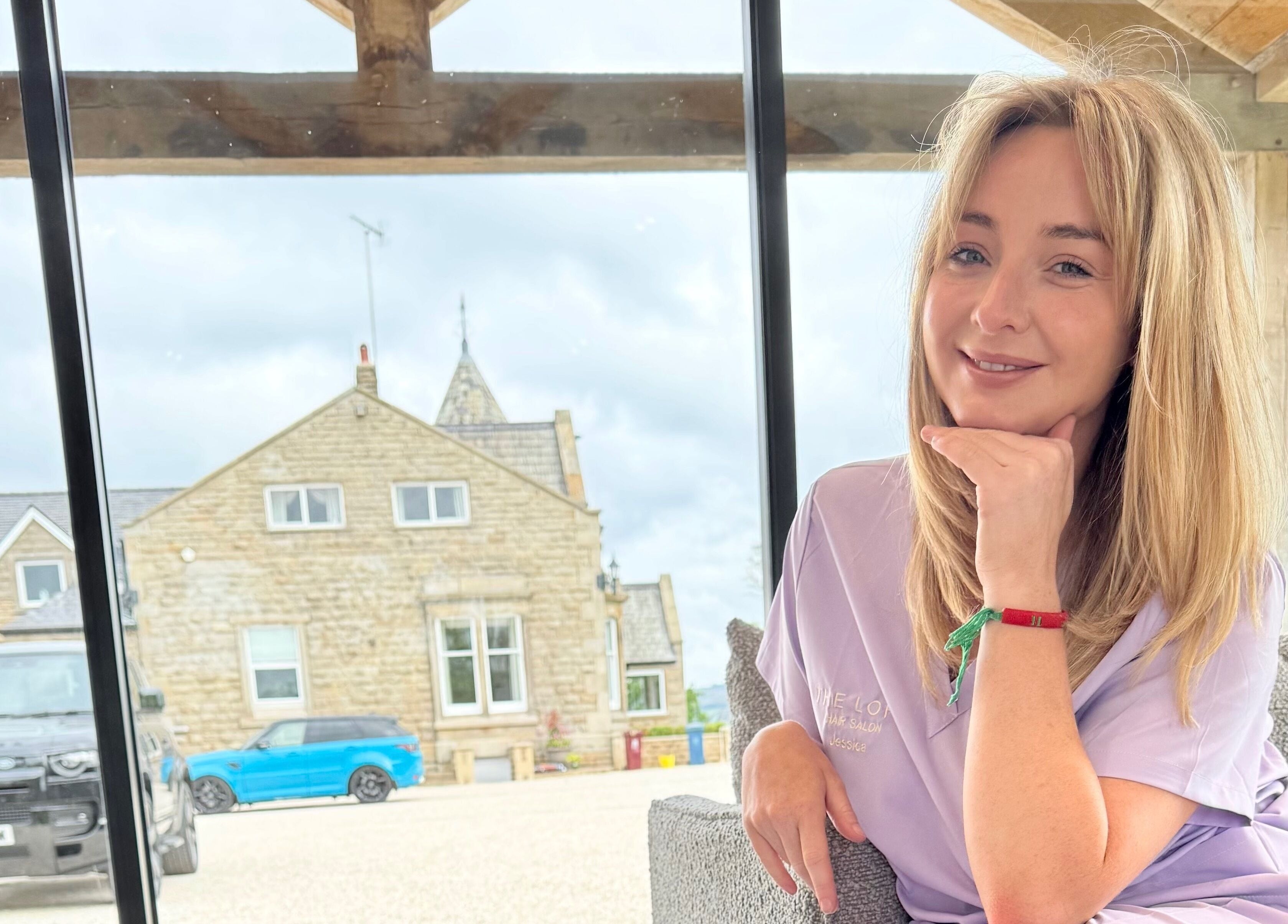 Woman smiling in front of The Loft BB7, Clitheroe, England, GB with rustic building in background.
