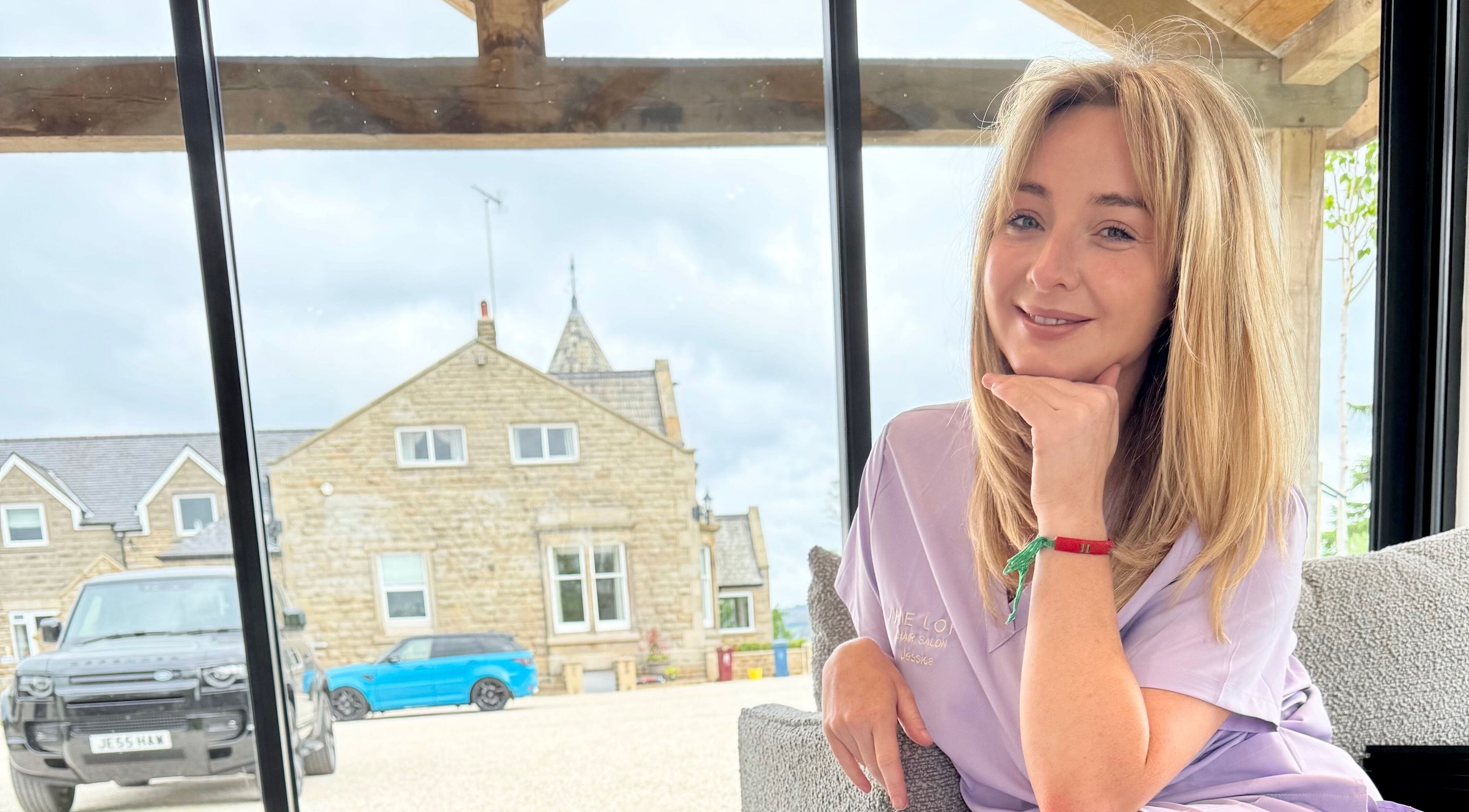 Woman smiling in front of The Loft BB7, Clitheroe, England, GB with rustic building in background.