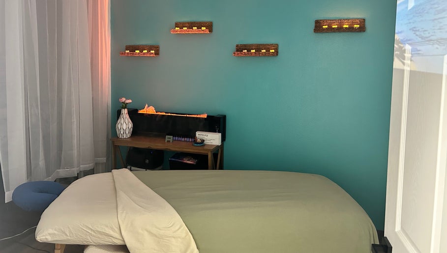 Relaxing massage room at BelaVita Wellness, Winter Garden, Florida, US with serene teal wall and warm lighting.