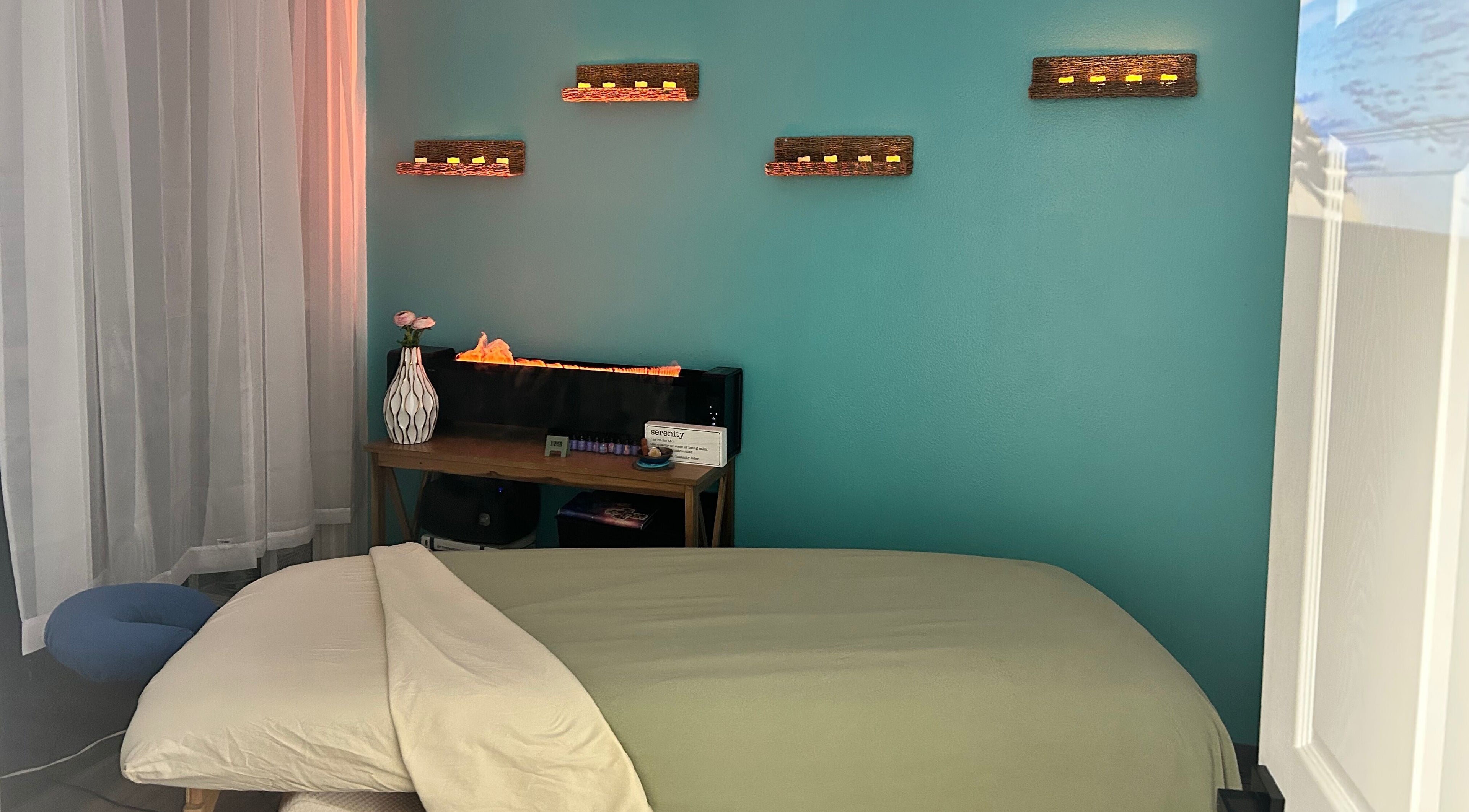 Relaxing massage room at BelaVita Wellness, Winter Garden, Florida, US with serene teal wall and warm lighting.