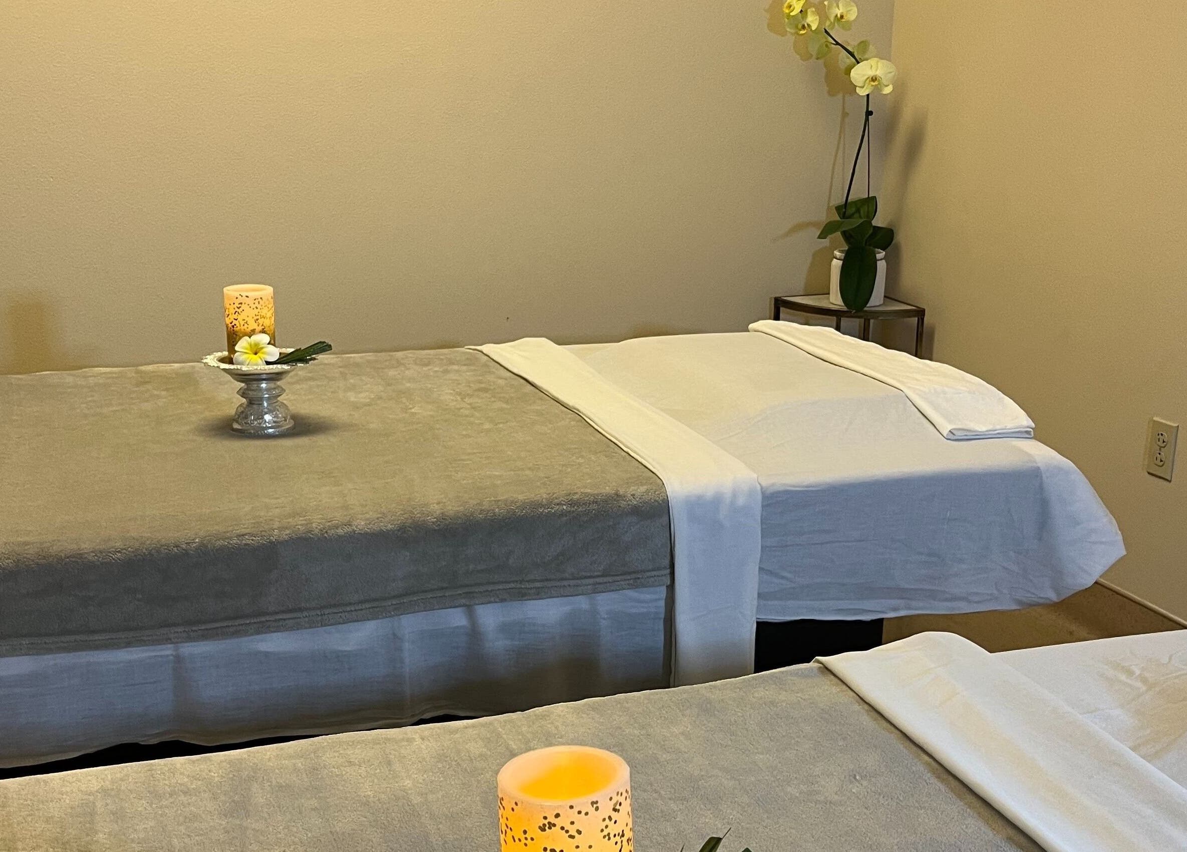 Calming massage room at Bua Thai Massage, Las Vegas, Nevada with two beds and decorative candles.