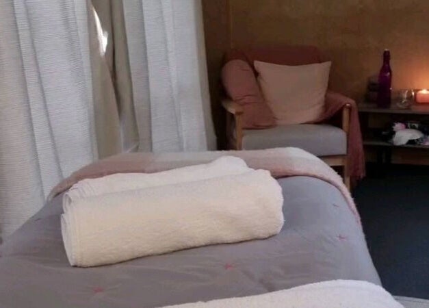 Relaxing massage room at The Palms Studio, Waihi, Waikato, NZ, featuring a comfortable bed and ambient lighting.
