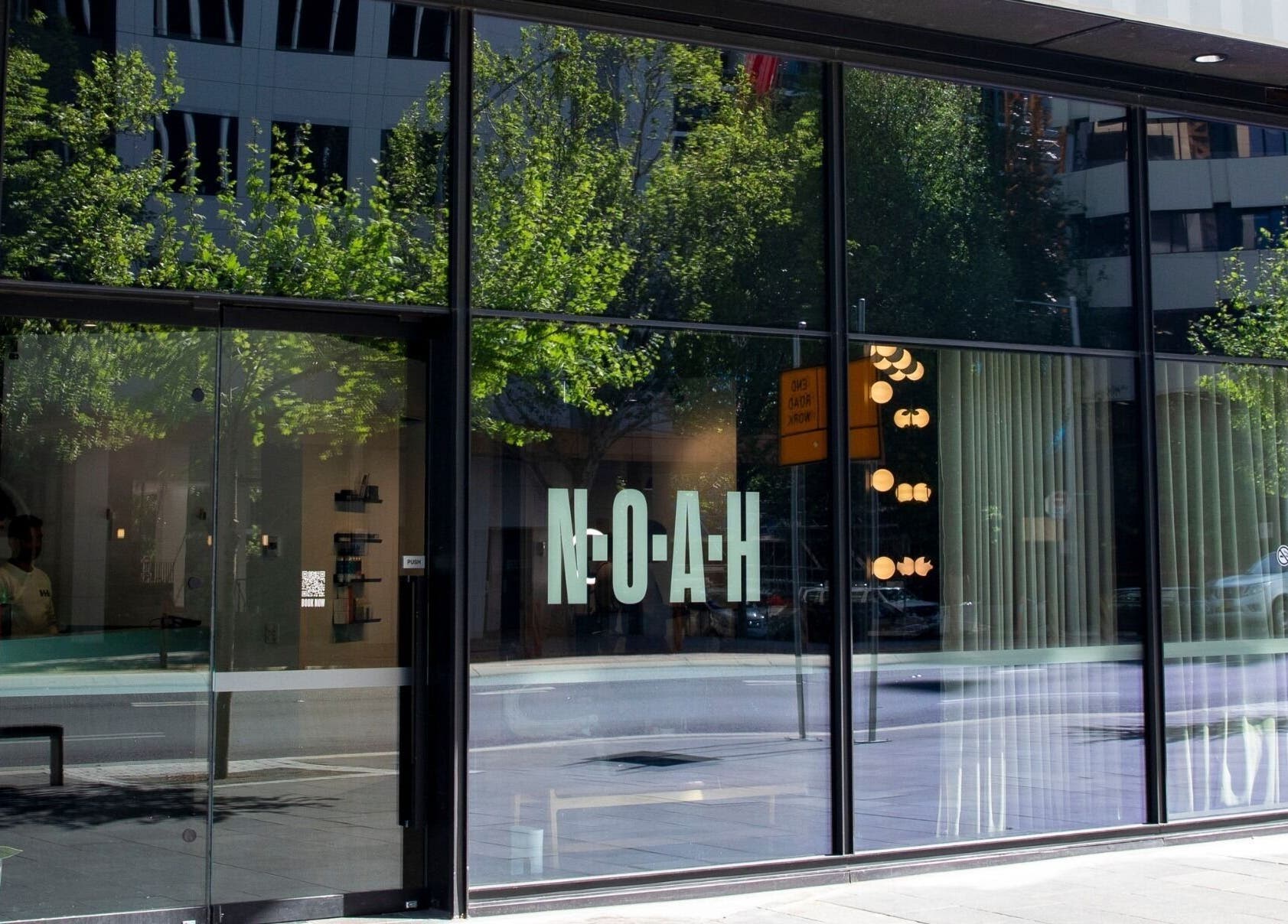 Front glass facade of NOAH Canberra, reflecting urban streetscape in Canberra, Australian Capital Territory, AU.