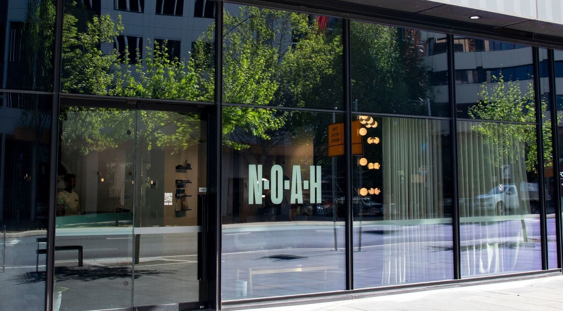 Front glass facade of NOAH Canberra, reflecting urban streetscape in Canberra, Australian Capital Territory, AU.