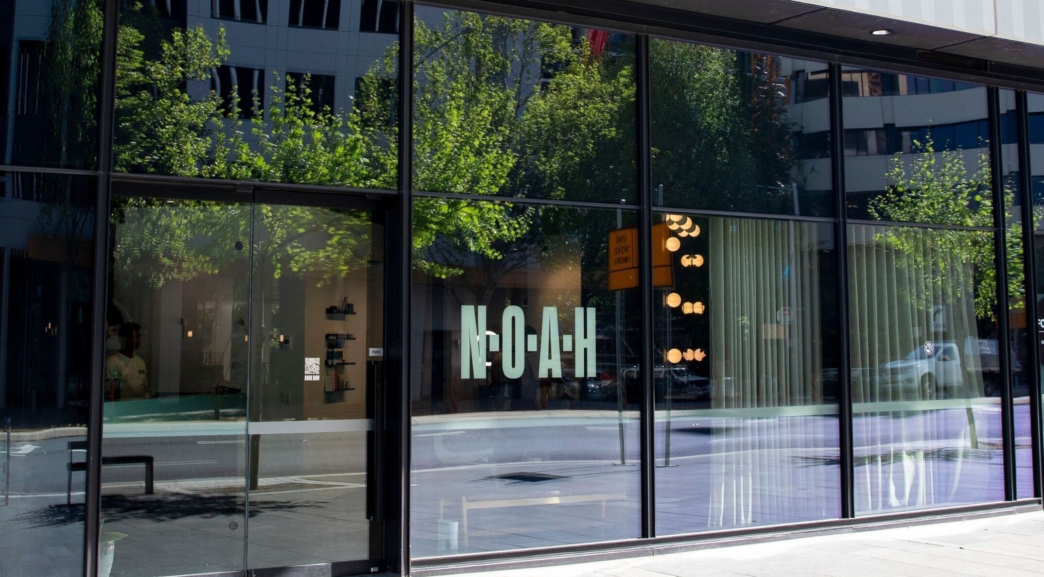 Front glass facade of NOAH Canberra, reflecting urban streetscape in Canberra, Australian Capital Territory, AU.