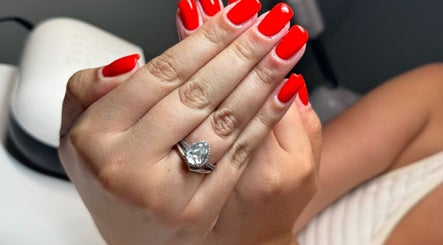 Vibrant red manicure with a ring at Soothe & Glow, Bletchley, England, GB.