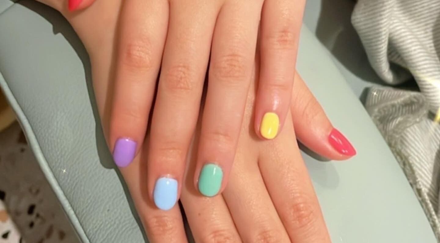 Colorful manicure at ABBY NAIL SALON in Bangkok, TH featuring vibrant red, purple, blue, green, and yellow nails.