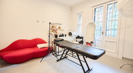 Modern beauty treatment room at Angelina Samko, Bondi Junction, New South Wales, AU with red sofa and equipment.