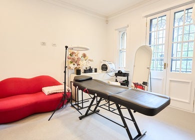 Modern beauty room at Angelina Samko, Bondi Junction, New South Wales, AU with red sofa and massage bed.