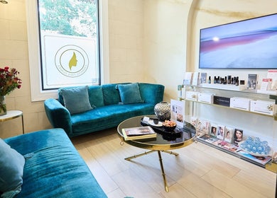 Elegant lounge at Angelina Samko, Bondi Junction, New South Wales, AU with teal sofas and skincare products displayed.