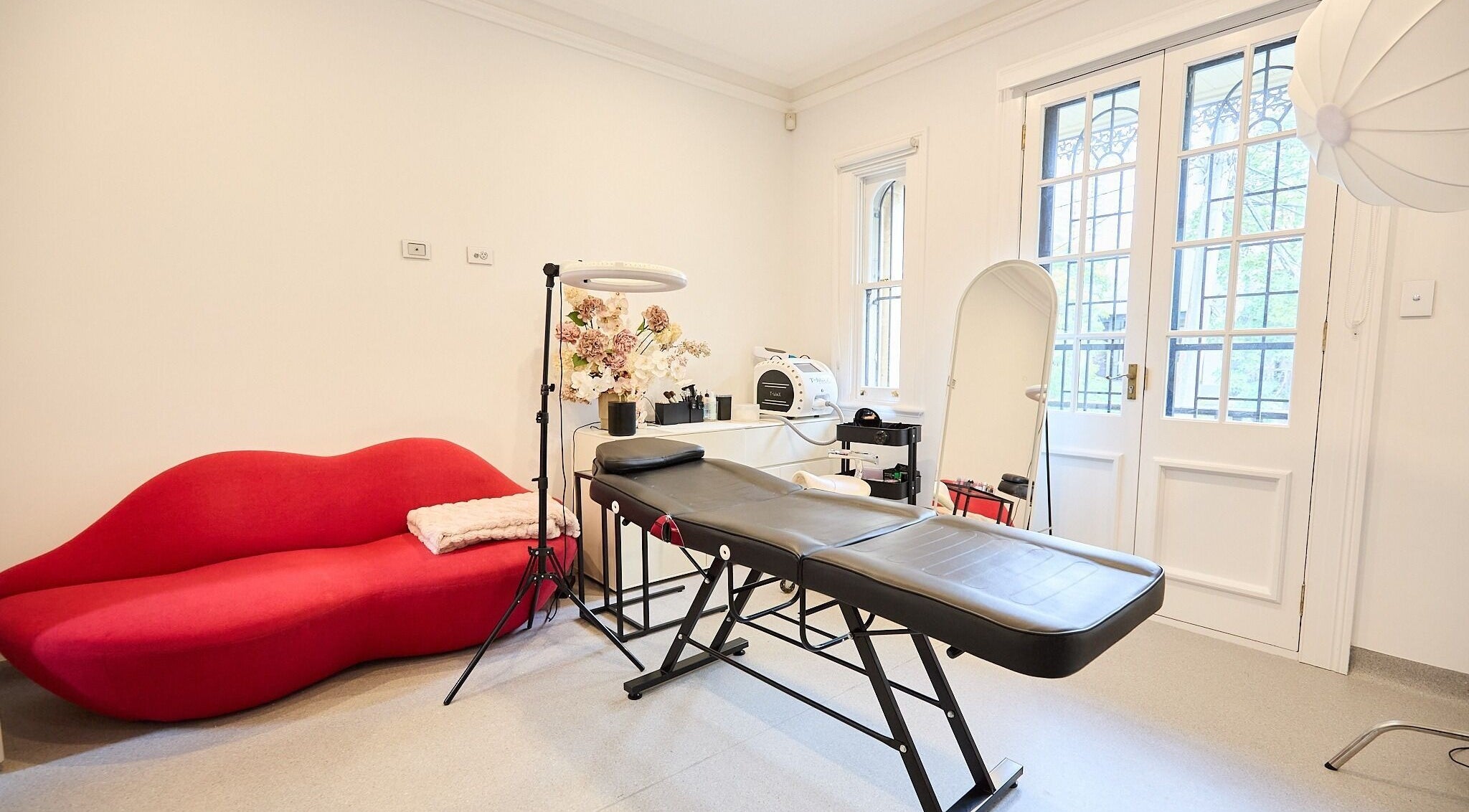 Elegant beauty treatment room at Angelina Samko, Bondi Junction, New South Wales, AU, featuring a red sofa.