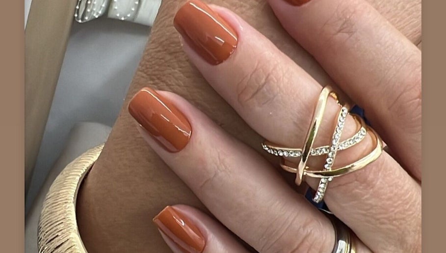 Manicure elegante com esmalte laranja e anéis dourados no Gessy Hair Cabeleireiros, Taubaté, São Paulo, BR.