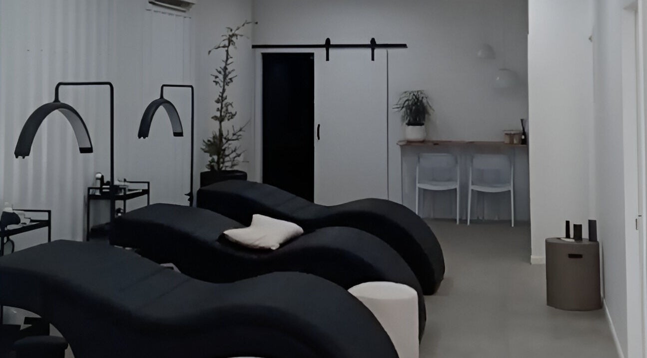 Relaxing treatment room at Lainey Everett Aesthetics in Whangaparāoa, Auckland, NZ with modern black loungers.