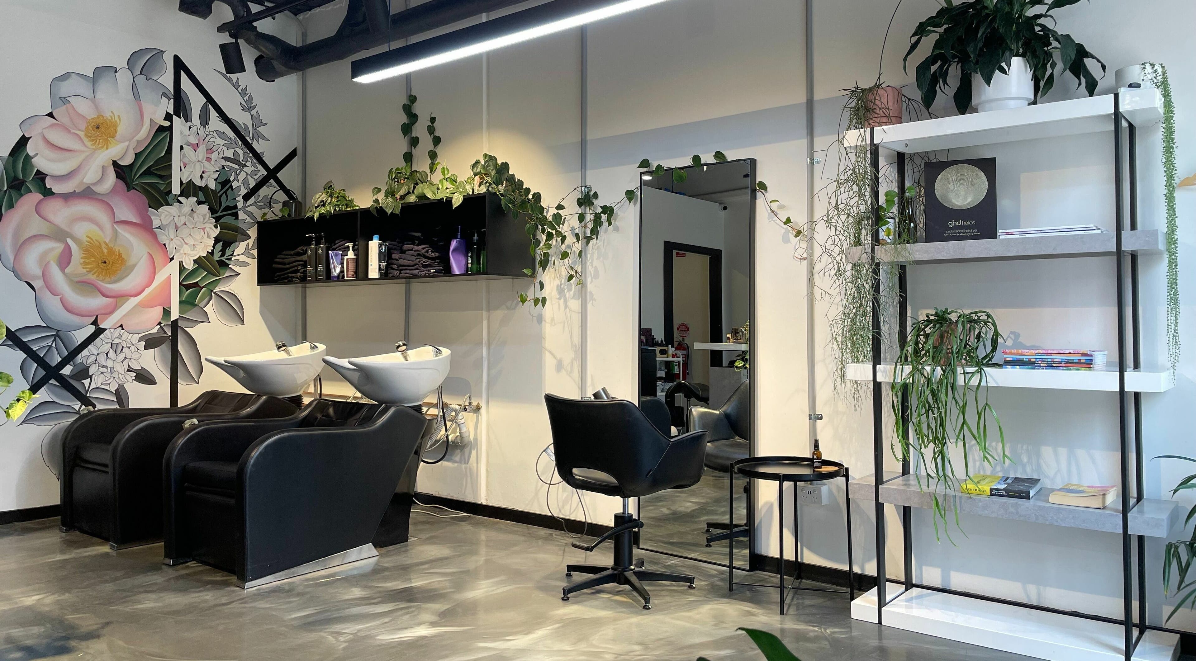Stylish interior of Mini Hairspace in Melbourne, Victoria, AU, with floral mural, wash stations, and greenery.