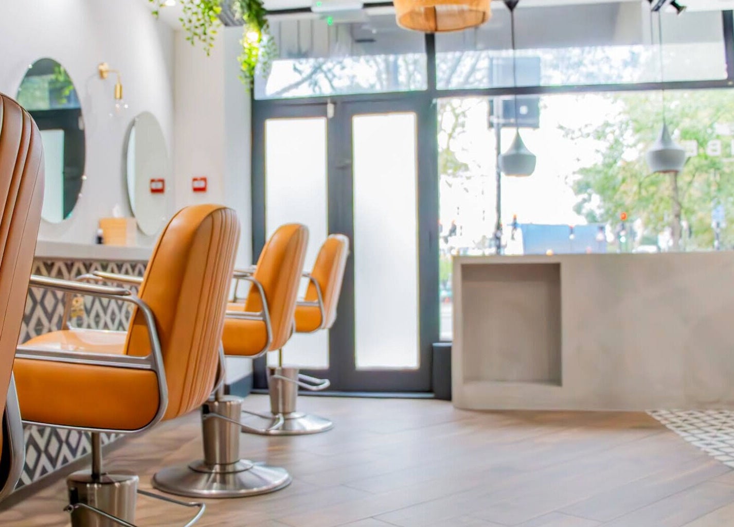 Modern hair salon interior at Tribe Academy - Clapham Common, London, England, GB with stylish orange seats.