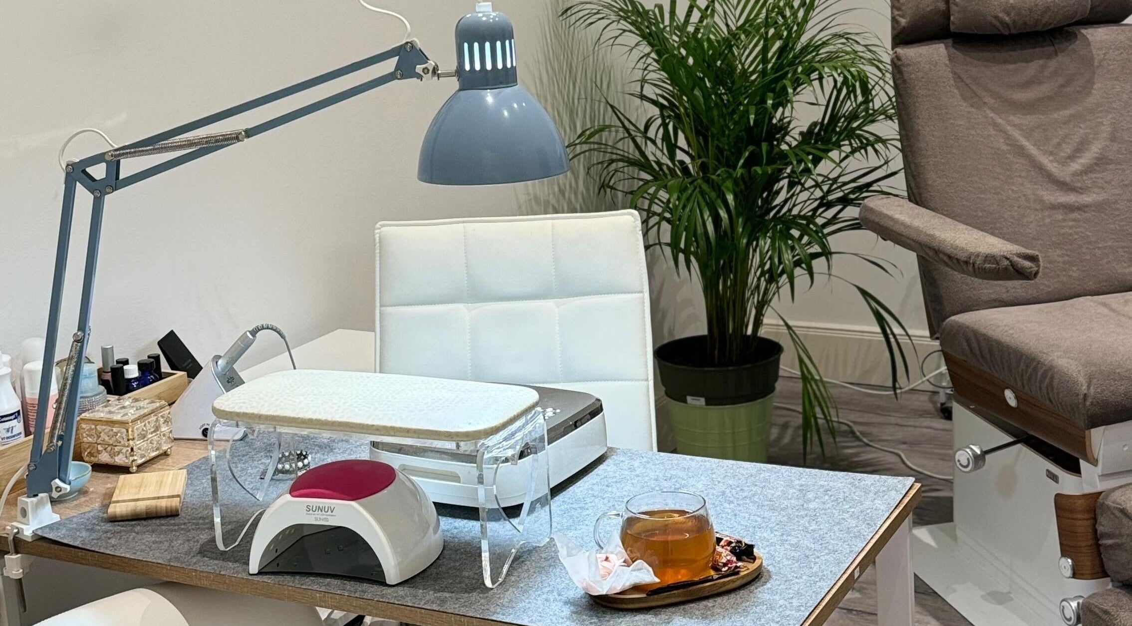 Maniküre-Tisch bei Krasota.Hamburg, Hamburg, DE mit Nagellack, Lampe und Tee.