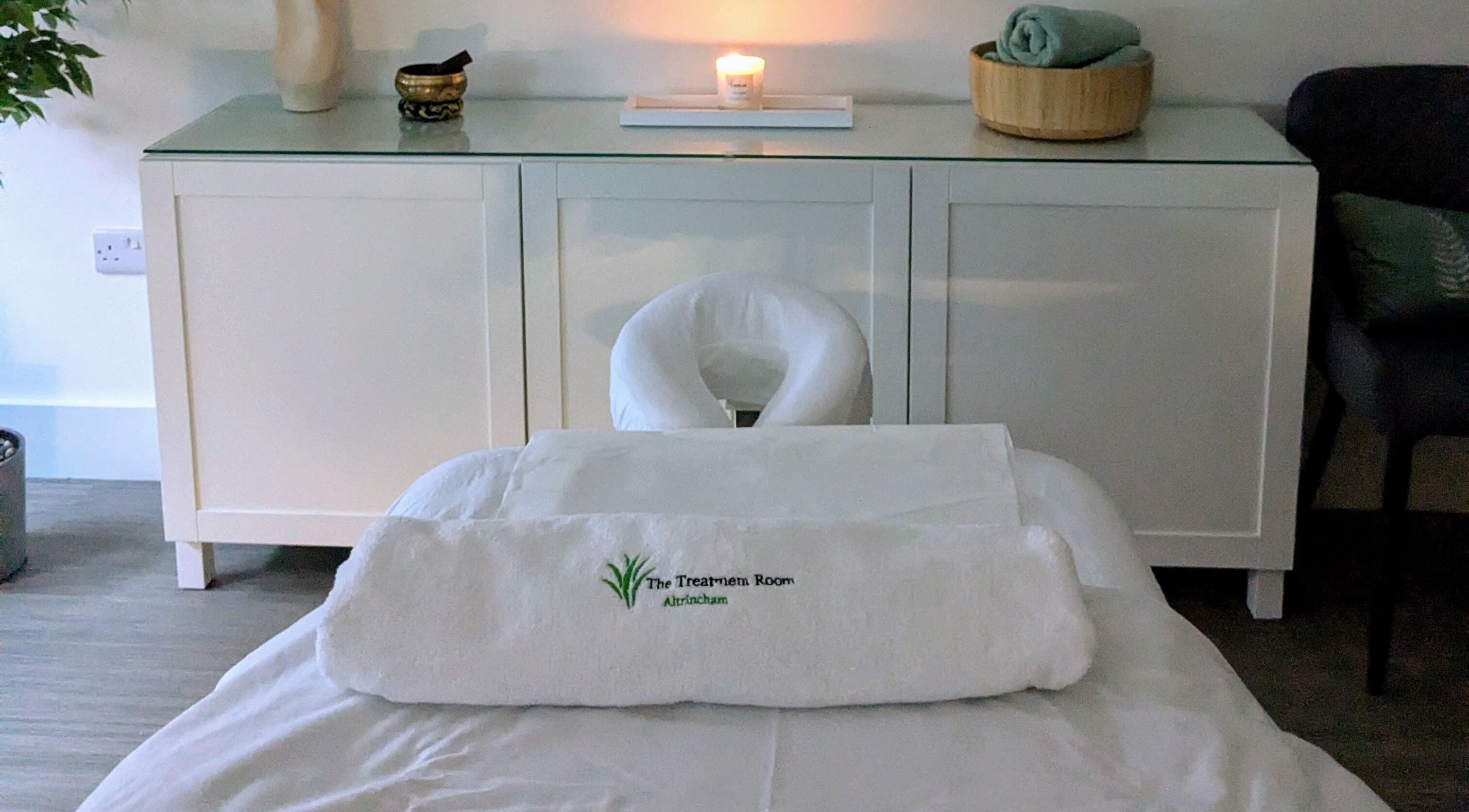 Relaxing treatment room at The Treatment Room Altrincham, Cheshire, England, GB with massage table and candle.