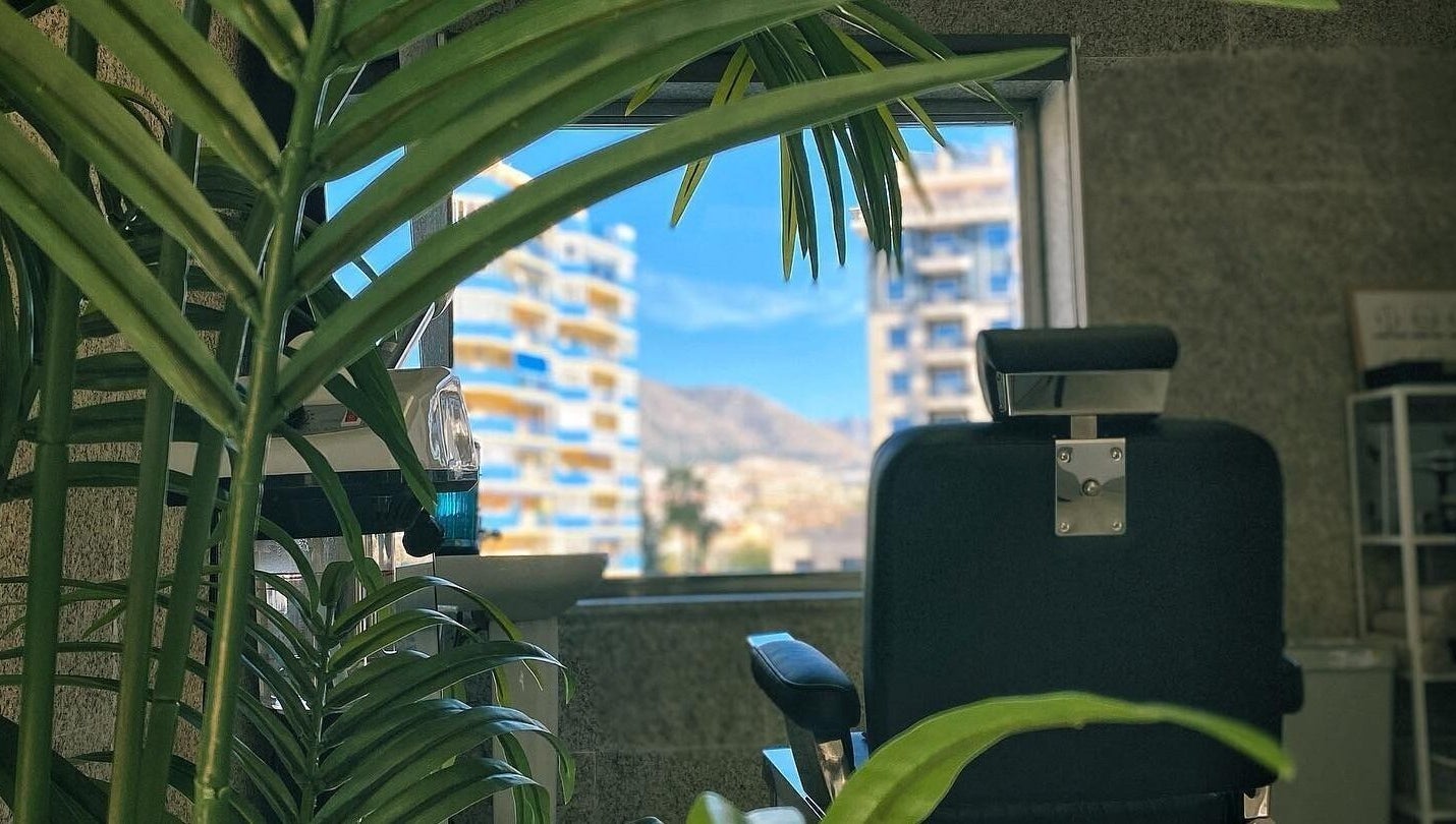 Silla de barbería en Buenos Amigos Barber Studio, Fuengirola, Andalucía, ES, con vista de la ciudad.