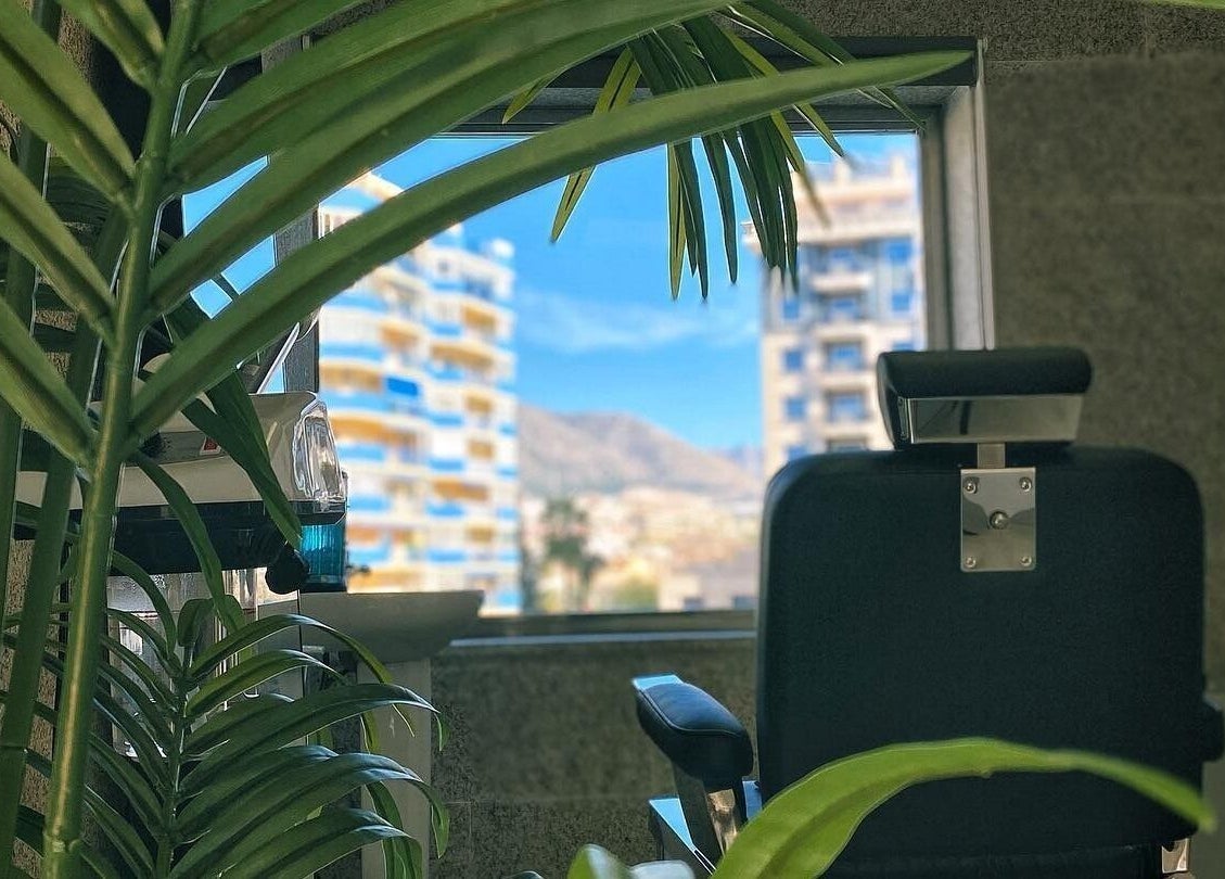 Silla de barbería en Buenos Amigos Barber Studio, Fuengirola, Andalucía, ES, con vista de la ciudad.