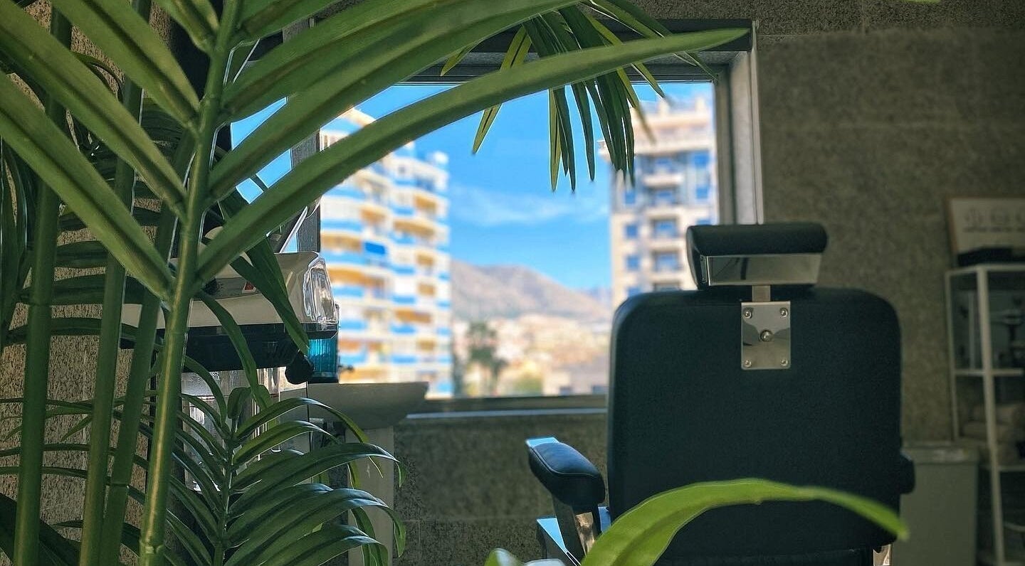 Silla de barbería en Buenos Amigos Barber Studio, Fuengirola, Andalucía, ES, con vista de la ciudad.