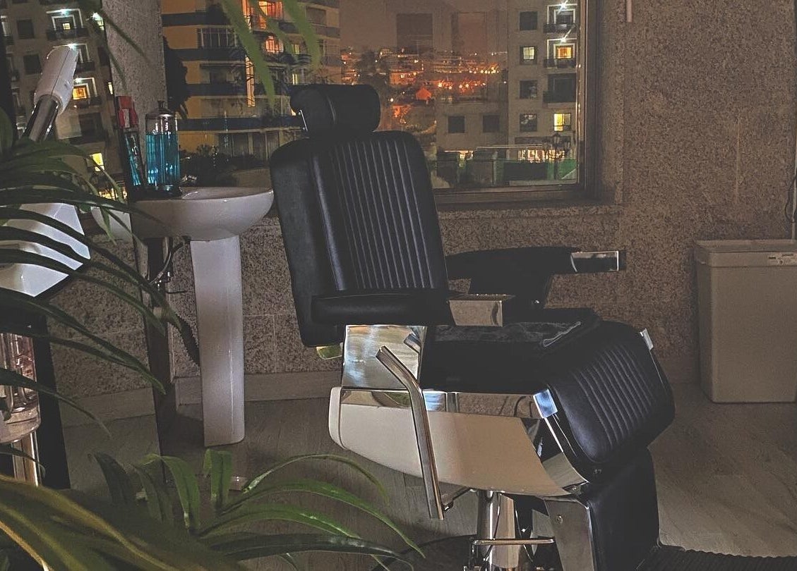 Interior nocturno de Buenos Amigos Barber Studio, Fuengirola, con silla de barbero elegante y vista urbana.