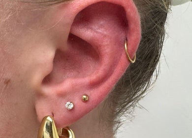 Close-up of ear with gold and diamond piercings at ER Laser Clinic, Wisbech, England, GB.