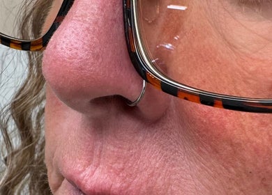 Nose piercing at ER Laser Clinic & Piercing in Wisbech, England, GB. Close-up of face with glasses and nose ring.