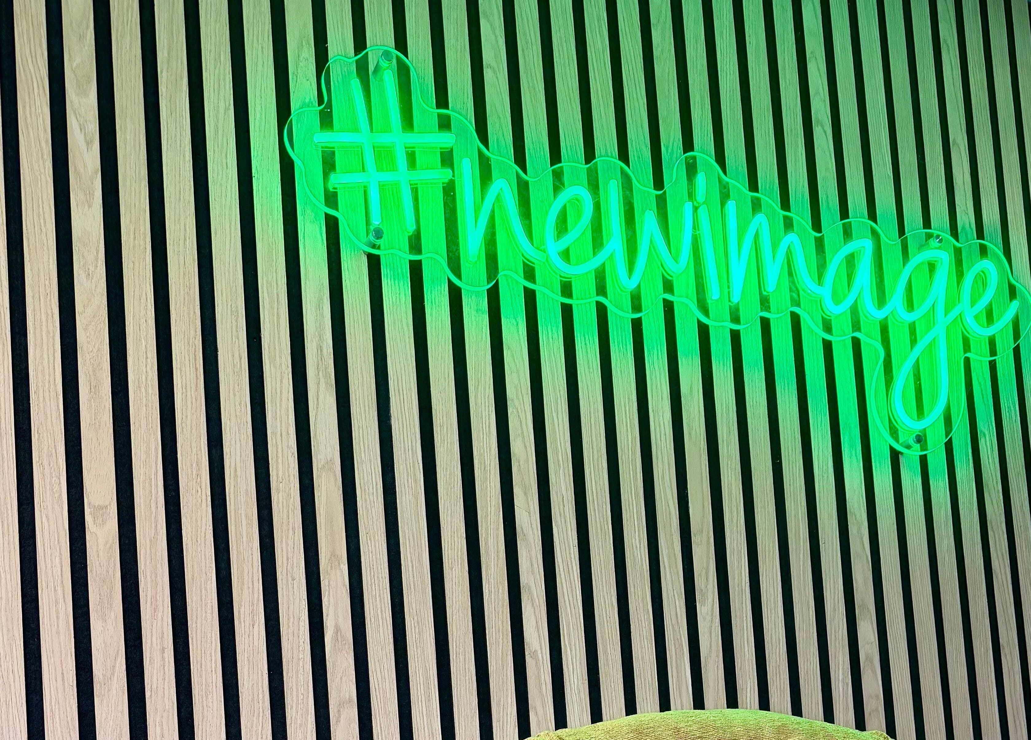 Green neon sign on wooden paneling at ER Laser Clinic & Piercing, Wisbech, England, GB.