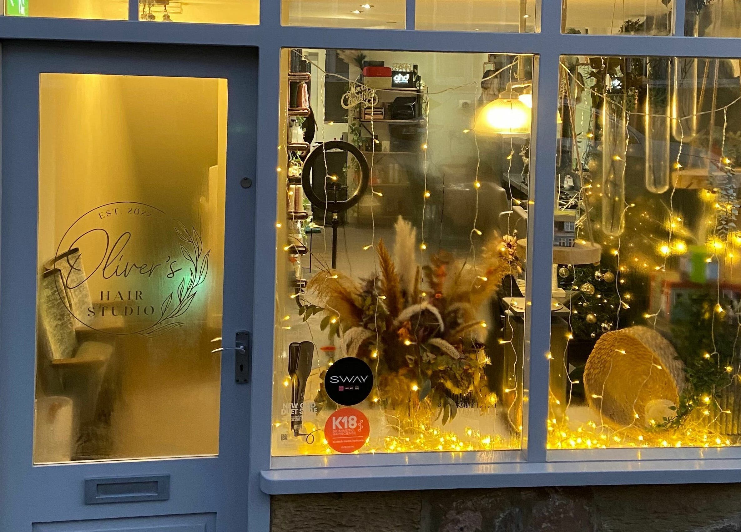 Front view of Oliver's Hair Studio Limited in Belper, England, illuminated with warm, decorative lights.