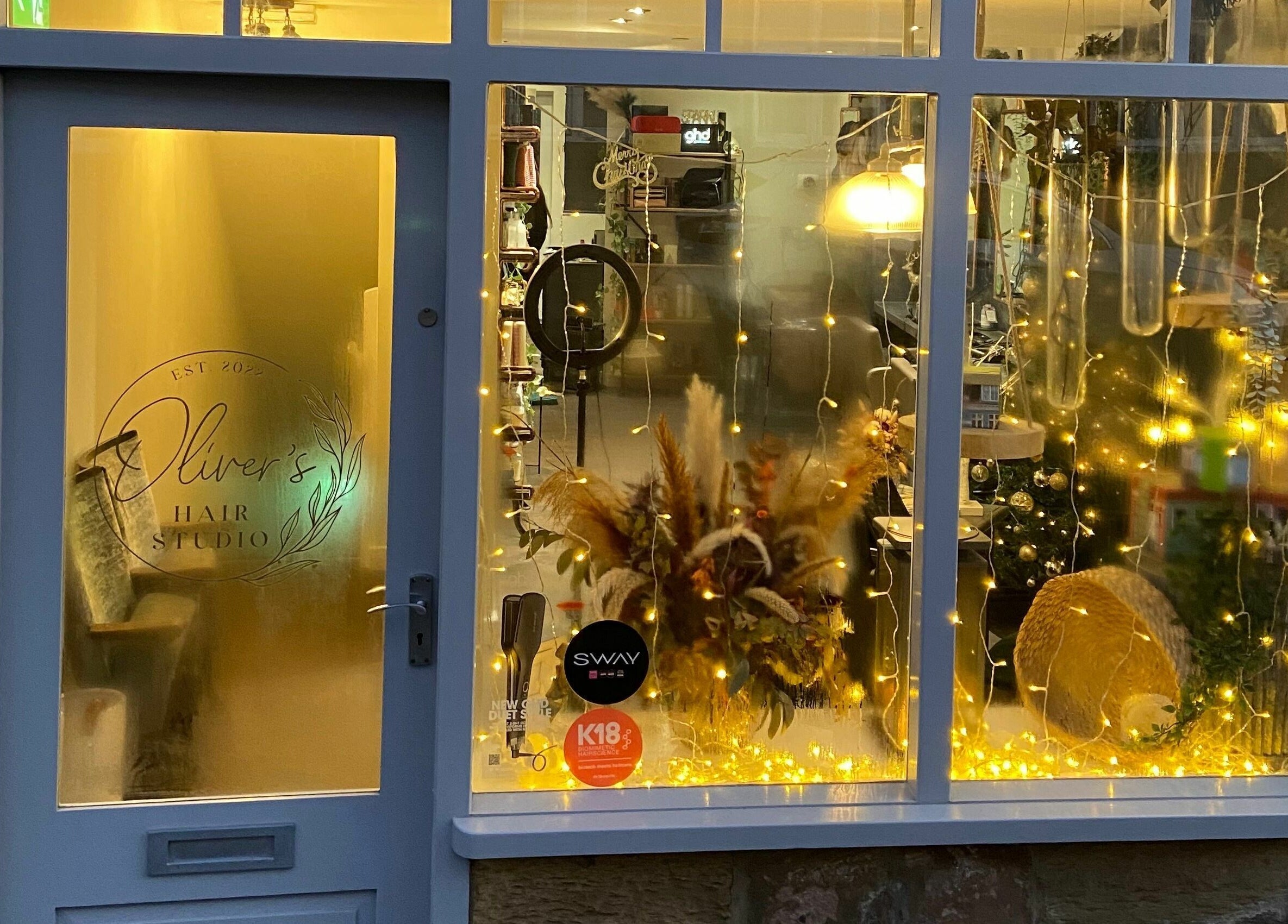 Front view of Oliver's Hair Studio Limited in Belper, England, illuminated with warm, decorative lights.