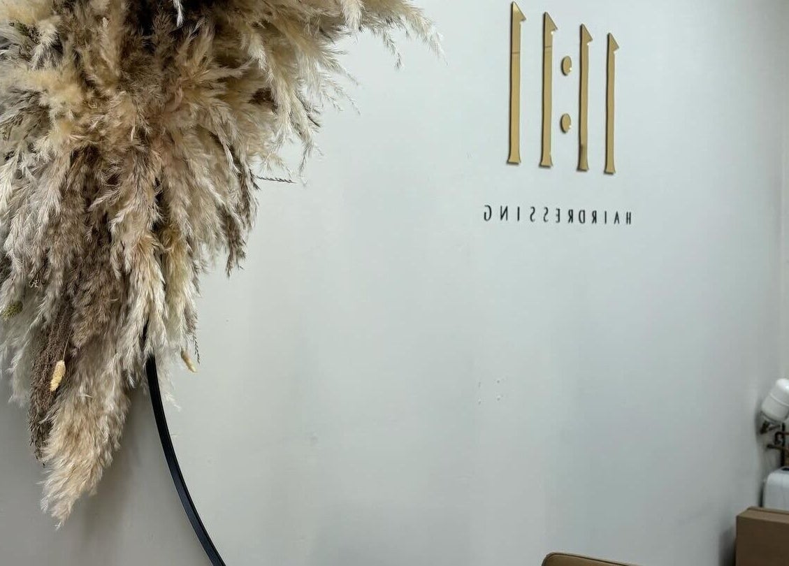 Reflection of 11:11 Hairdressing logo in Wrexham, Wales, GB with decorative feather design.