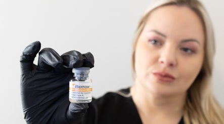 Specialist at Impeccable Aesthetics Warrington showcasing a Botox vial for beauty treatments.