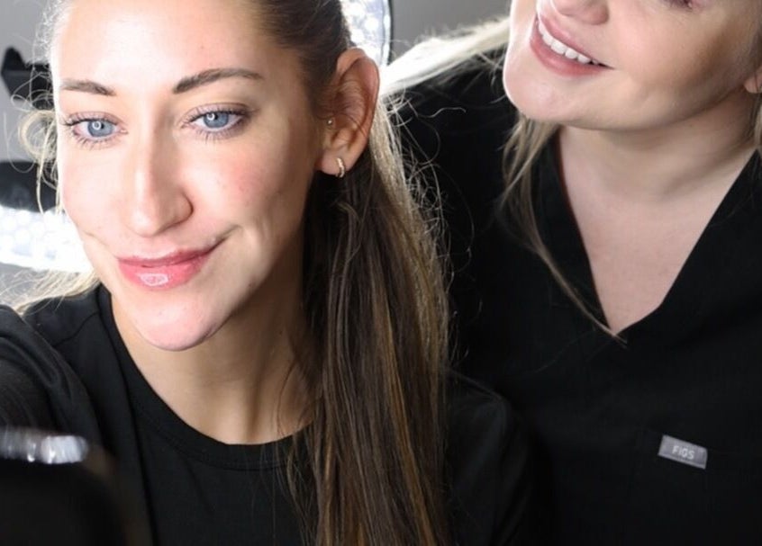 Two women at Impeccable Aesthetics, Warrington, England, GB, smiling during a beauty treatment session.
