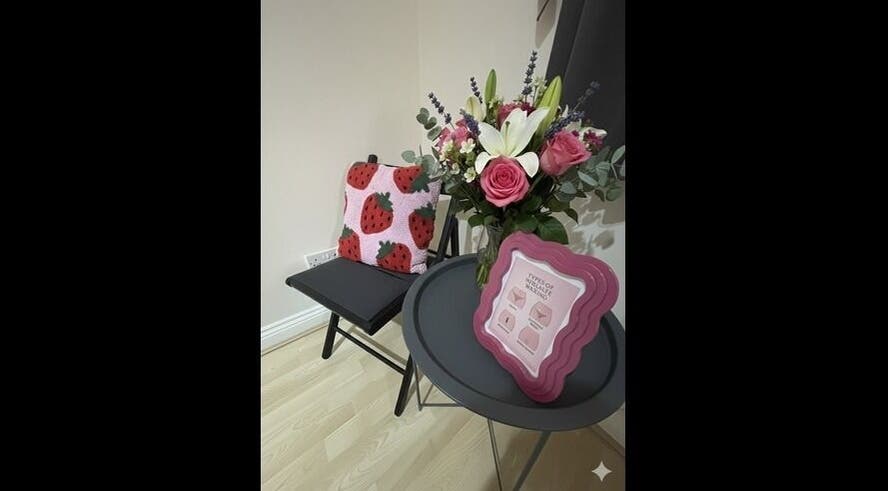 Cozy corner at Wax Wurks, Paignton, England with floral decor and strawberry-themed pillow.