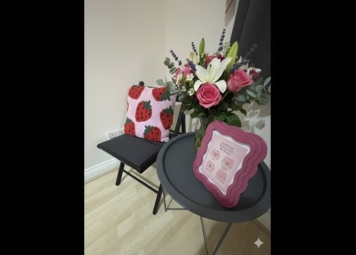 Inviting seating area at Wax Wurks, Paignton, England, GB featuring floral decor and a strawberry pillow.