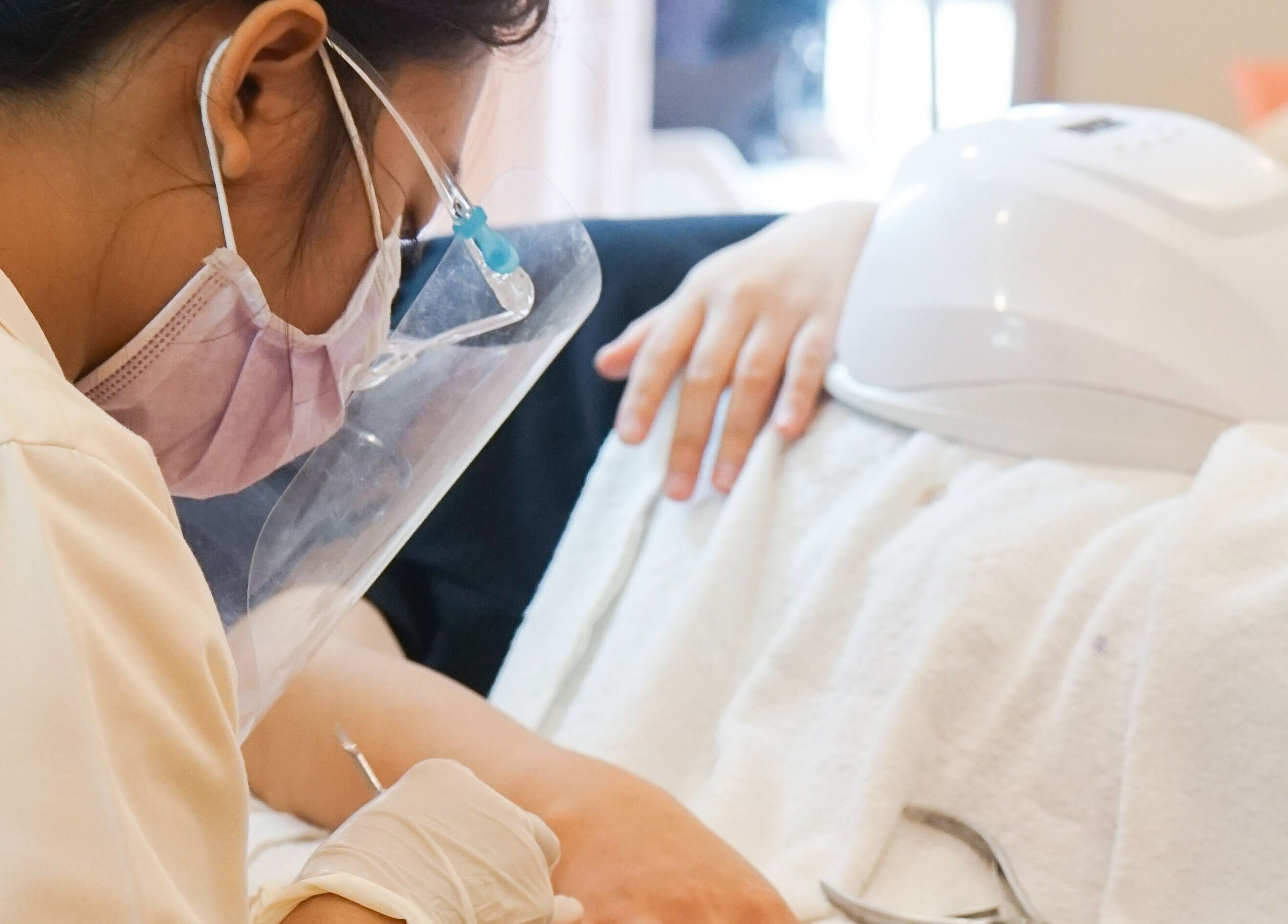 Professional nail care service at Bounce Beauty Bar, Jawa Timur, ID. Technician focuses on client's hand treatment.
