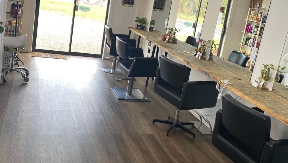 Modern salon interior at Uneek Hair, Tanilba Bay, New South Wales, AU, featuring stylish black chairs and wood accents.