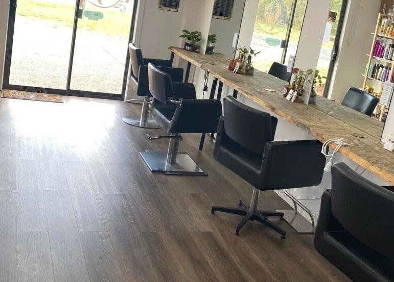 Modern salon interior at Uneek Hair, Tanilba Bay, New South Wales, AU, featuring stylish black chairs and wood accents.