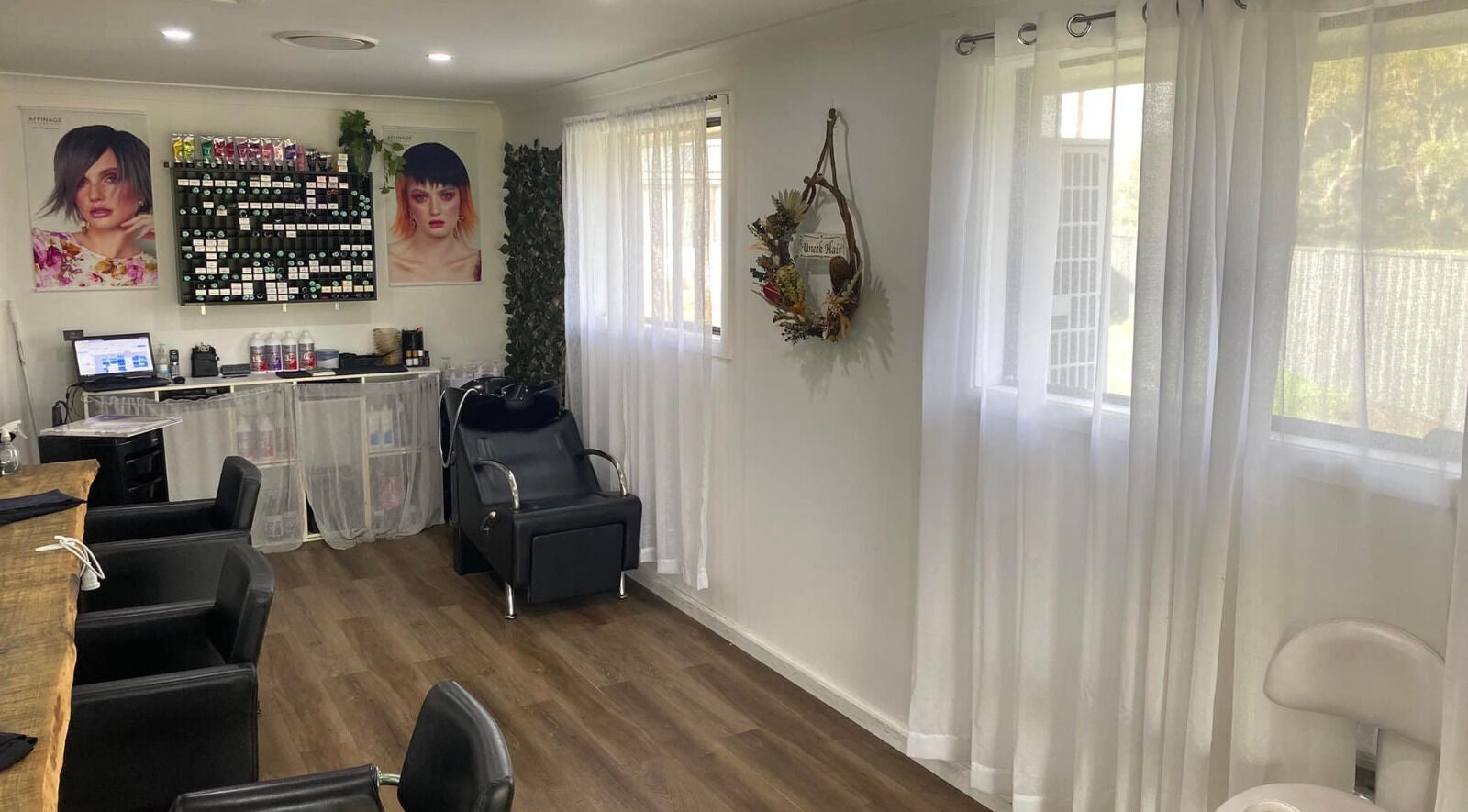 Inviting interior of Uneek Hair, Tanilba Bay, New South Wales, AU with modern chairs and styling products.