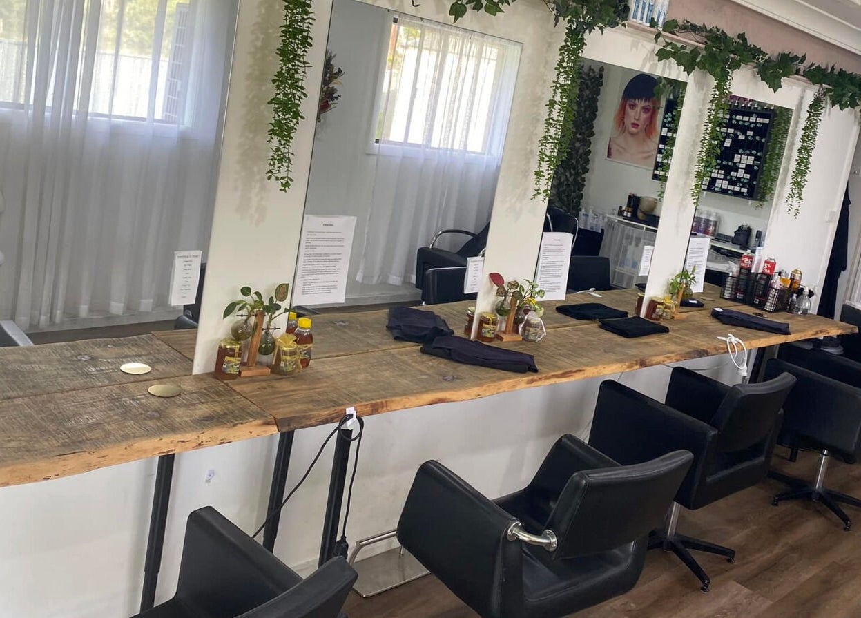 Elegant hair salon interior at Uneek Hair, Tanilba Bay, New South Wales, AU, featuring stylish black chairs and mirrors.