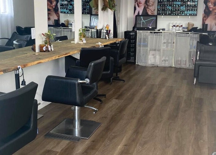 Modern chic salon interior at Uneek Hair, Tanilba Bay, New South Wales, AU, featuring sleek chairs and rustic decor.
