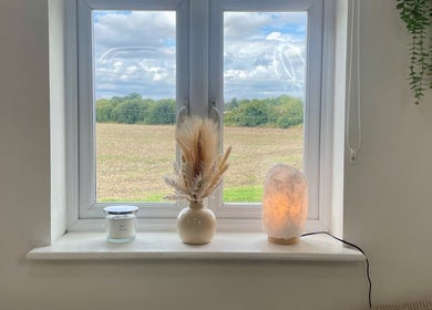 Peaceful window view at Heidi Turner Beauty in Paddock Wood, England with vase, candle, and lamp.