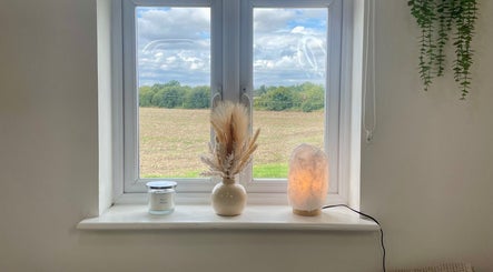 Peaceful window view at Heidi Turner Beauty in Paddock Wood, England with vase, candle, and lamp.