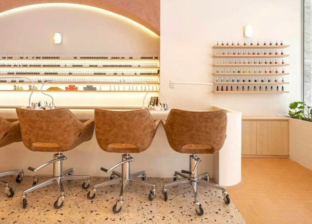 Modern nail salon at Blushing on Hunter, Newcastle, New South Wales, AU showcasing sleek chairs and nail polish wall.