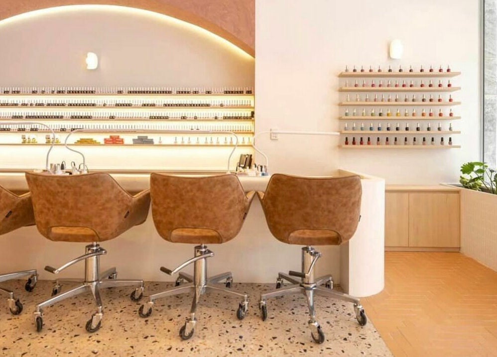 Modern nail salon at Blushing on Hunter, Newcastle, New South Wales, AU showcasing sleek chairs and nail polish wall.
