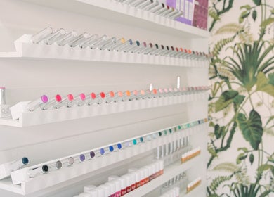 Colorful nail polish display at Wild Beauty, London, England, GB with tropical wall design.